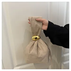 Close-up of beige suede bucket bag featuring a golden pebble-shaped metal ring closure