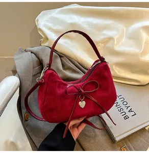 Detail of burgundy suede tote with bow and heart pendant on business attire background