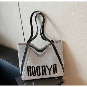 Vue macro détaillée de la texture toile grise avec lettrage noir HOOAYA sur le sac