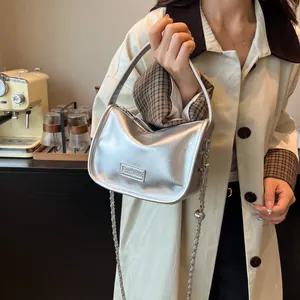 Silver metallic mini crossbody bag with Fashion plaque and chain strap shown on a model