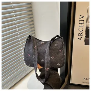 Close-up of denim underarm bag with pastel bow embroidery and double shoulder straps