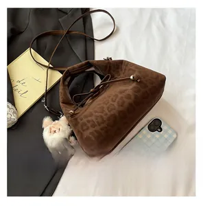 Detail of leopard print bucket bag with drawstring closure and cute plush charm
