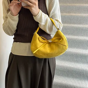 Yellow suede crescent tote bag with 3D bow and silver heart charm shown on model