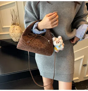 Close-up of retro leopard print handbag with plush charm and bow detail in hand