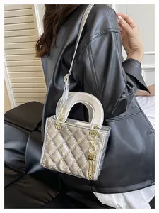 Detail of silver quilted leather handbag with gold key charm and metallic hardware