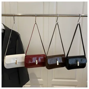 Detail of four glossy patent leather shoulder bags in white, red, brown, and black colors