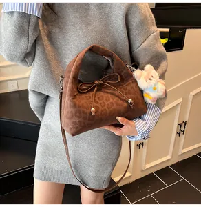 Close-up of leopard print crossbody bag with velvet fabric and plush puppy charm detail