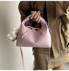 Detail of soft pink dumpling bag with drawstring and white plush bear charm