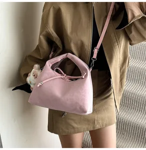 Detail view of pink crossbody dumpling bag with a cute white bear plush charm on a model