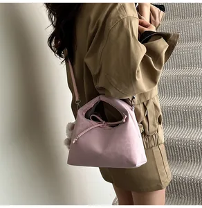 Detail of pink nylon dumpling bag with drawstring knot and white pompom on model