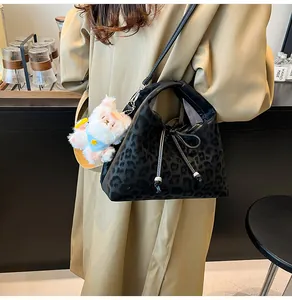 Detail of black leopard print crossbody bag with cute white plush rabbit charm