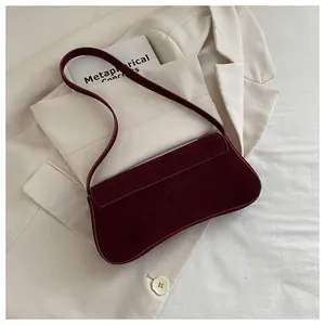 Detailed texture of burgundy suede underarm bag on a beige minimalist blazer