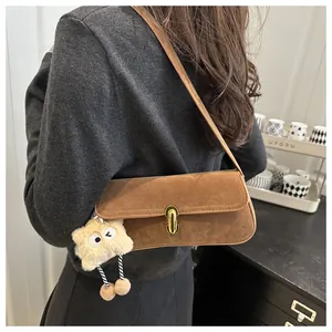 Detail of vintage brown suede baguette bag with gold lock and plush monster charm