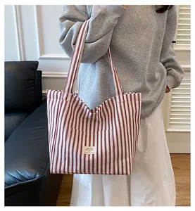 Detail of red and white striped canvas tote bag with a front pocket and textile label