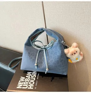 Detail of blue leopard print handbag with plush bear charm and drawstring closure