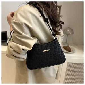 Detalle del bolso de hombro negro con textura de leopardo y ribete de metal dorado