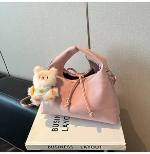 Detail of pink dumpling bag with pleated faux leather texture and plush bear charm