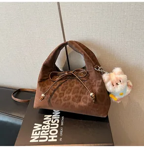 Detail of coffee brown leopard print dumpling bag with suede texture and plush bear charm