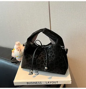 Detail of black leopard print dumpling bag with drawstring closure and plush bear charm