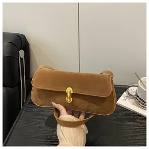 Macro detail of brown suede underarm bag with elegant golden oval metal clasp