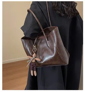 Detail of dark brown leather tote bag featuring a cute plush bunny charm and sleek handles