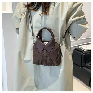 Braune Beuteltasche mit kreativem Hemdkragen-Design und Griff am Modell gezeigt