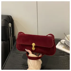 Detail of vintage burgundy suede shoulder bag with a polished gold oval twist lock