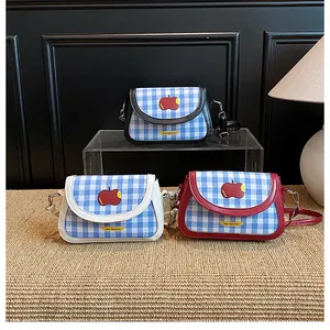 Detailed view of three checkered shoulder bags with apple prints and diverse color trims