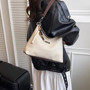 Modische Canvas- und Leder-Achseltasche mit Perlenkette von einem Model getragen