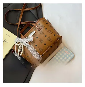 Détail d'un sac seau vintage avec monogramme d'ours, nœud en dentelle et perles