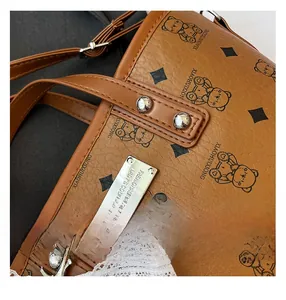 Vue macro du sac seau en cuir marron avec imprimé ours et détails métalliques