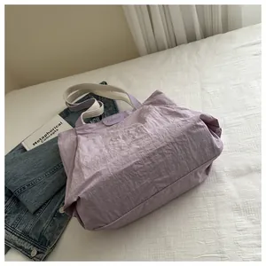 Vue détaillée du sac fourre-tout en nylon froissé violet clair avec écusson mode et anse