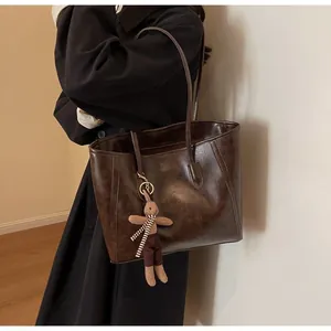 Brown vintage tote bag featuring textured leather and a cute plush rabbit charm