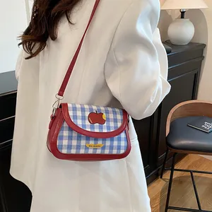 Blue and white plaid crossbody saddle bag with red leather trim and apple print detail
