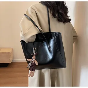 Detailed view of black faux leather tote bag with grainy texture and a cute bunny charm