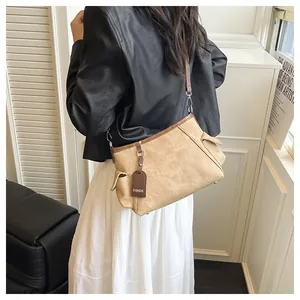 Detail of a beige canvas bucket bag with brown leather trim and adjustable silver buckle
