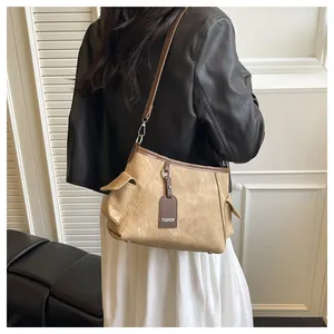 Detailed close-up of khaki bucket bag with brown trim and fashion tag on model