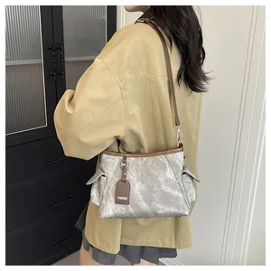 Silver-grey bucket bag with brown leather trim and fashion tag shown on a model