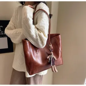 Detail view of the brown retro tote bag with a cute plush bunny pendant on the side