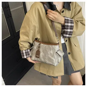 Detail of grey bucket bag with brown leather trim and side pockets on a model