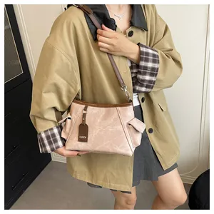 Detail of color-block bucket bag showing contrast side pocket and fashion tag on model