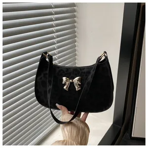 Détail du sac sous l'aisselle à motif léopard noir avec boucle papillon dorée