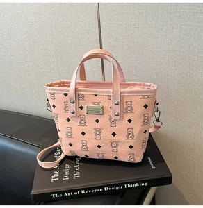 Détail du sac seau rose avec imprimé ours et plaque métallique argentée logo