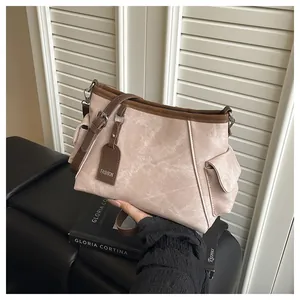 Detail of light pink bucket bag with brown contrast trim and fashion tag on leather bench