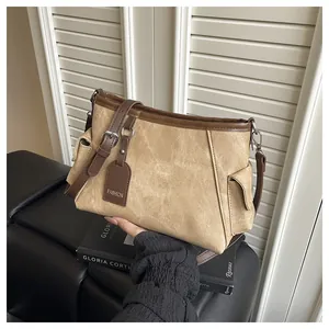 Detail of khaki canvas bucket bag with brown leather trim and fashion tag in hand