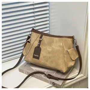 Detail view of khaki faux suede bucket bag with side buckle pockets and brown trim