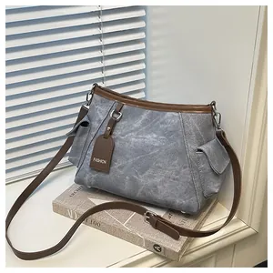 Close-up of grey washed canvas bucket bag with brown leather trim and fashion tag
