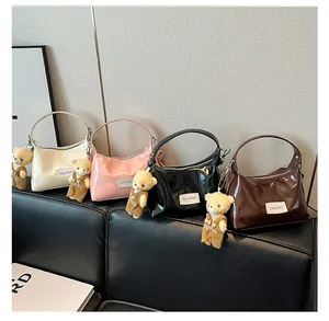 Detail showing four glossy faux leather handbags in pastel colors with cute bear charms