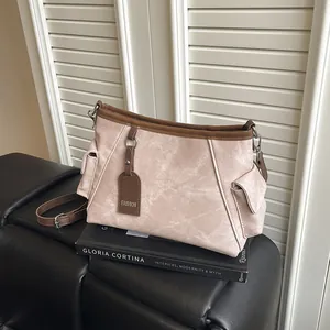 Pink moire texture bucket bag with brown trim and side pockets on a leather stool