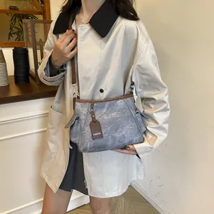 Chic grey-blue bucket bag with brown leather trim worn by model in a stylish trench coat